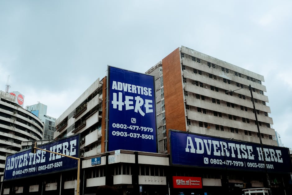 Large billboards on urban buildings displaying 'Advertise Here' in Lagos, Nigeria.
