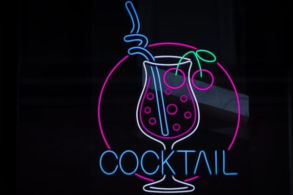 Colorful neon cocktail sign glowing on a dark background in Riga.
