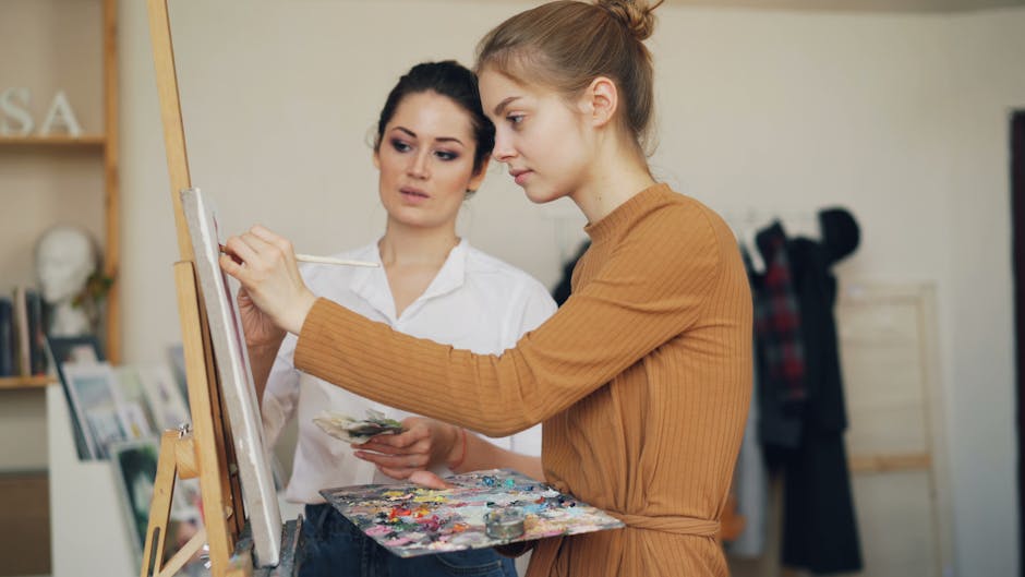 Two women engaged in painting and learning art techniques in a studio setting.