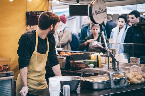 Dynamic scene of a street food vendor working in a busy market, engaging with diverse customers.