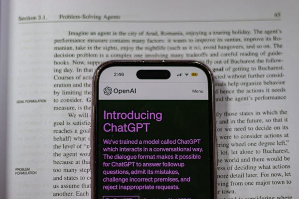 Smartphone showing OpenAI ChatGPT in focus, on top of an open book, highlighting technology and learning.