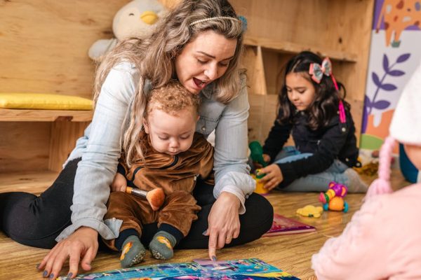 A mother and children enjoying interactive playtime on the floor in a cozy indoor setting.