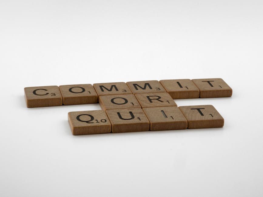 Scrabble tiles spelling 'Commit Or Quit' on a white surface, symbolizing decision-making.