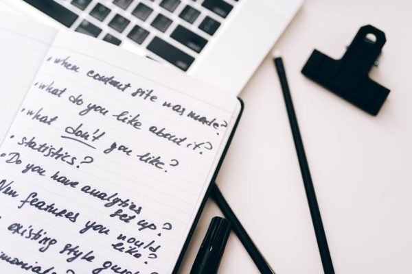 A close-up view of a notebook with handwritten notes alongside a laptop for planning and strategy.