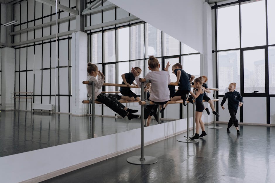 Kids engaging in ballet practice in a modern dance studio with large mirrors and natural light.