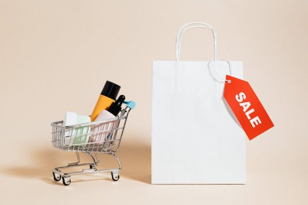 Minimalist image featuring a shopping cart with products and a sale-tagged bag.
