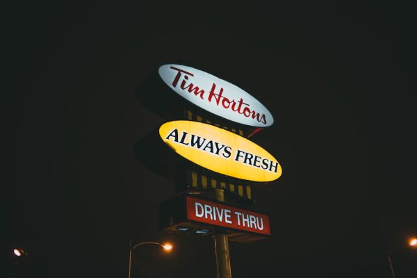 Illuminated Tim Hortons drive-thru sign glowing against a dark night sky.