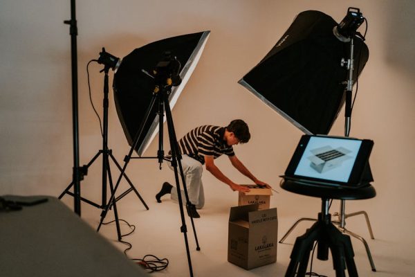 A professional studio scene with a man preparing packages under studio lighting, showcasing a modern photography setup.