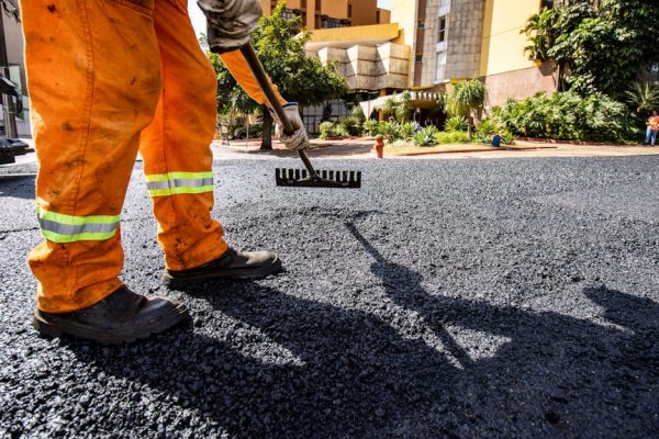 Worker in orange gear paving a road in Londrina city during daytime.
