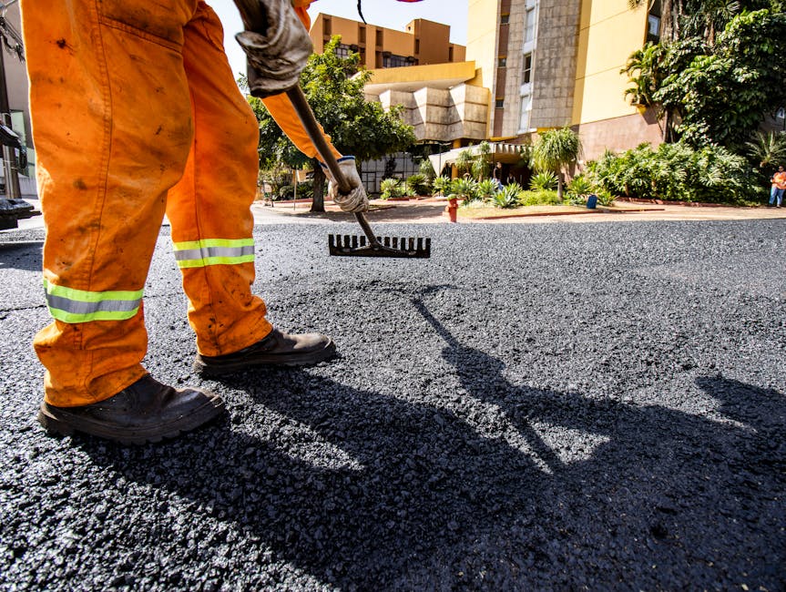 Worker in orange gear paving a road in Londrina city during daytime.