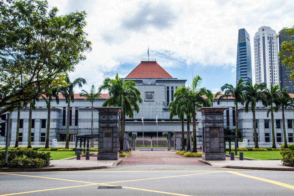 Exterior view of Singapore Parliament House with lush greenery and skyscrapers in the background.