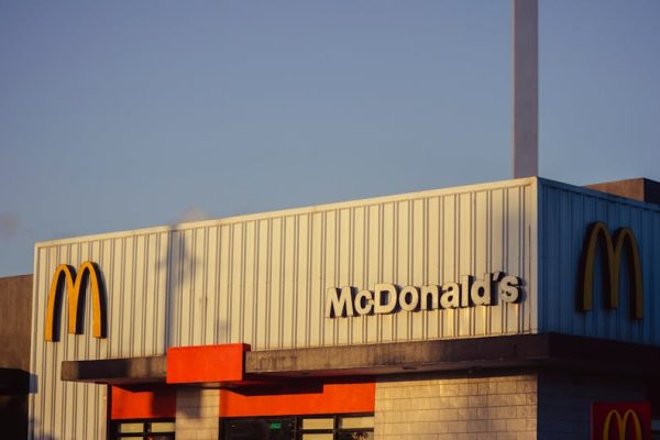 Photo of a McDonald's restaurant exterior under a clear sky, emphasizing its iconic architecture.