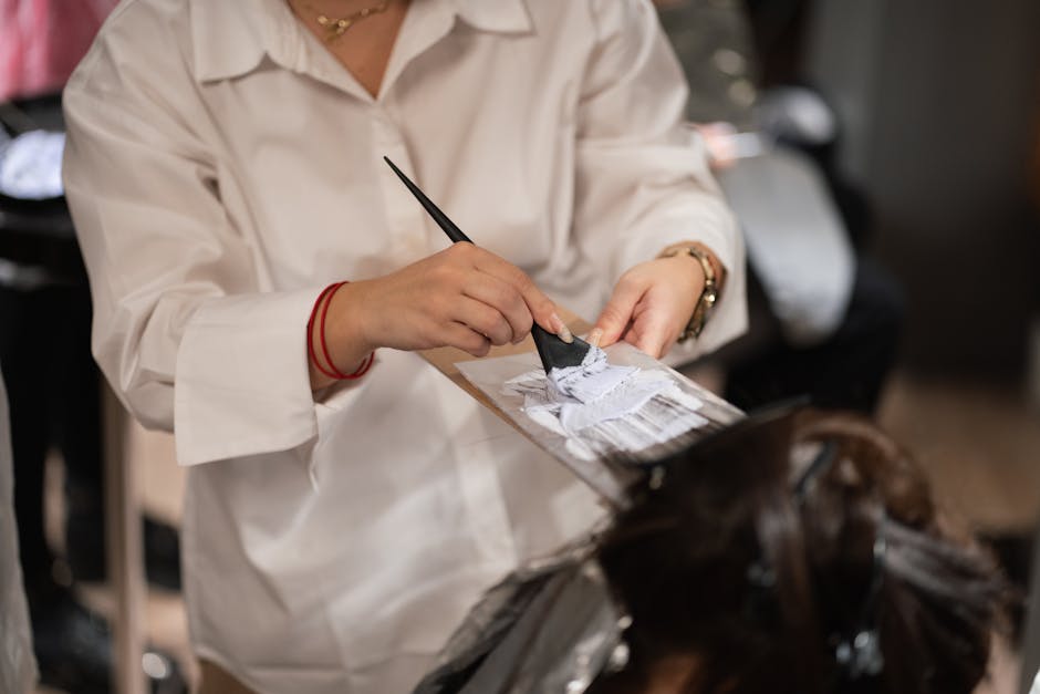 Close-up of a stylist applying hair color in a contemporary salon setting.