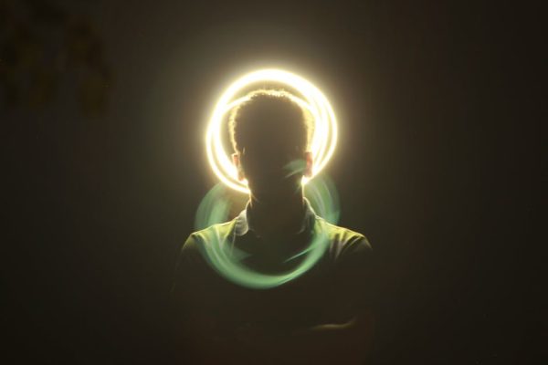 Artistic silhouette of a man with a vibrant halo light effect and motion blur on a dark background.