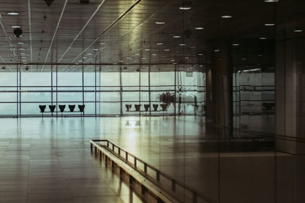 A calm and empty airport terminal in Singapore with a reflective glass facade and soft lighting.