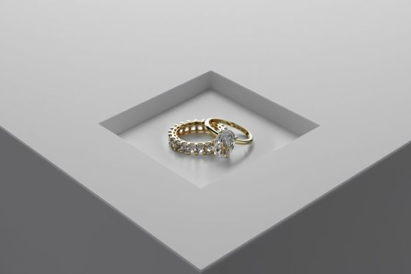A close-up of exquisite gold and diamond rings set on a minimalist surface.