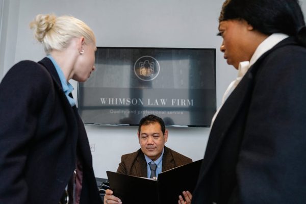 Diverse colleagues gathering in conference hall of law firm and discussing details of contract while working together