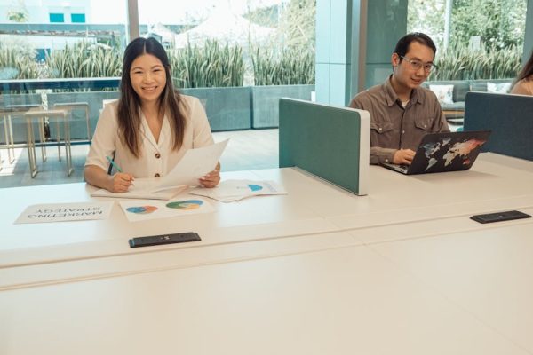 Smiling Asian colleagues working on marketing strategy in a bright, modern office.