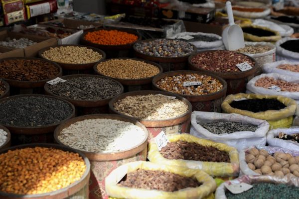 Various nuts and seeds displayed in baskets at an outdoor market, showcasing rich textures and colors.