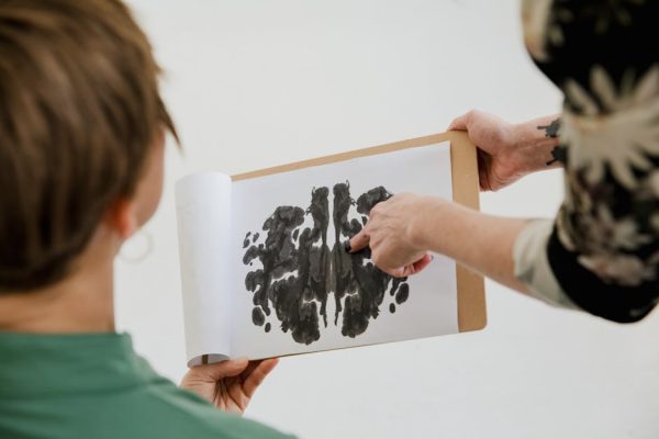A psychologist and patient discuss a Rorschach inkblot test during a therapy session.