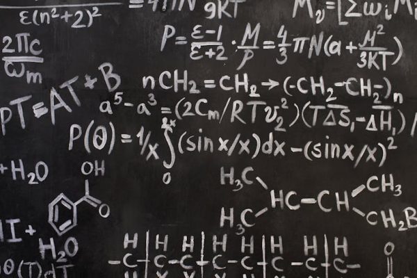 A close-up view of complex mathematical and chemical formulas on a blackboard.