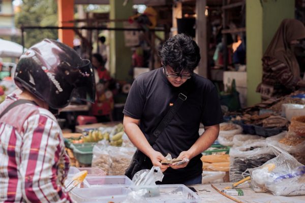 A man counting money at a bustling street market in Pontianak, Indonesia.