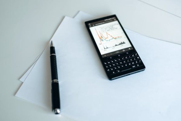 Smartphone displaying graphs on paper with a pen, perfect for business strategy concepts.