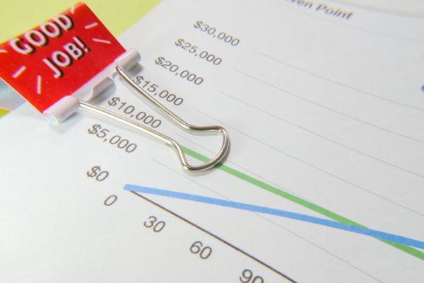 Close-up of a 'Good Job!' binder clip on a financial graph paper.