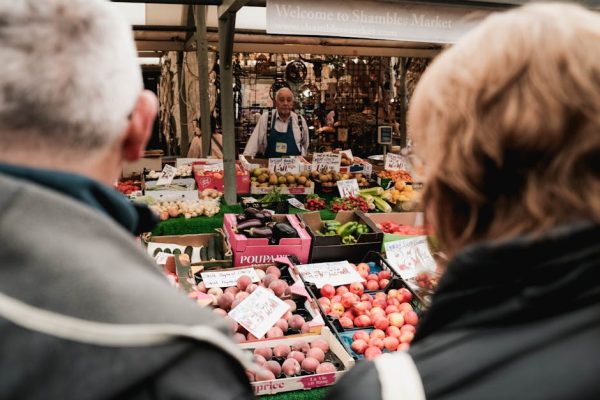 Crowds explore the colorful stalls at Shambles Market, York, bustling with fresh produce and vibrant life.