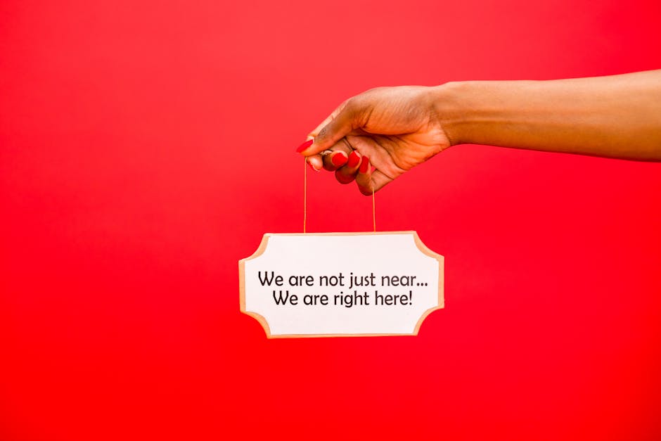 A hand holding a sign with text against a vivid red backdrop, perfect for communication themes.