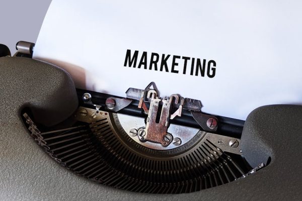 Close-up of a vintage typewriter with the word 'Marketing' on paper, conveying a retro business theme.