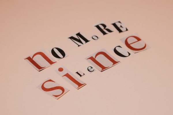 Typography artwork using cutout letters spells 'No More Silence' against a beige background.