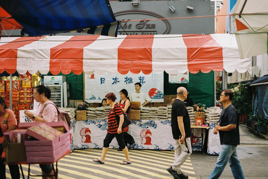 Colorful street market in Singapore with people shopping, vibrant stalls, and bustling environment.