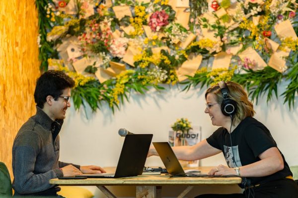 Two people recording a podcast in a stylish Luxembourg studio with floral decor.