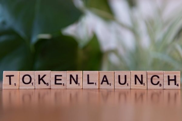 Scrabble tiles spelling 'Token Launch' on a vibrant green background.