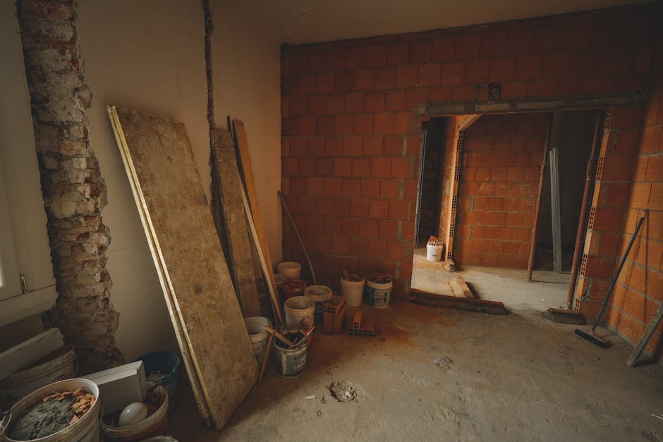 A red brick wall under construction with tools and materials scattered around in a renovation project.