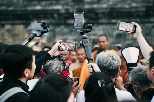 A crowd uses smartphones to capture a Buddhist ceremony at a historic site.