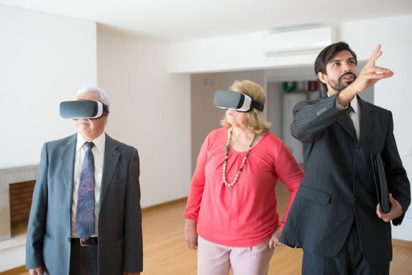 Senior couple using VR headsets in a modern apartment guided by a real estate agent.