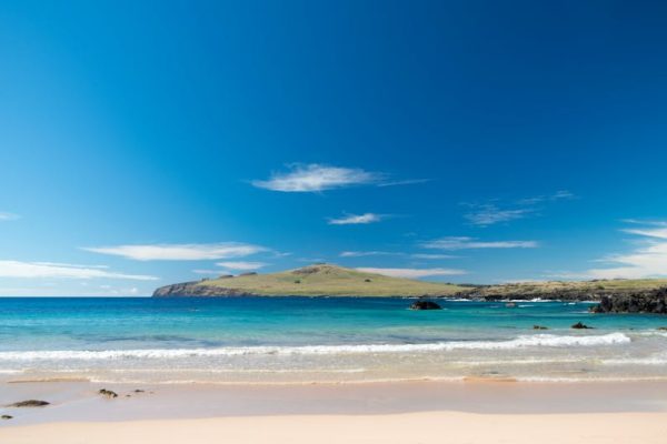 Captivating scene of a pristine beach with clear blue water and distant hills on Easter Island.