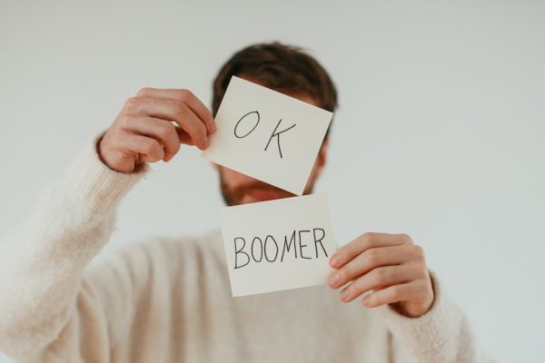 A person holding two cards with 'OK Boomer' written in bold text.