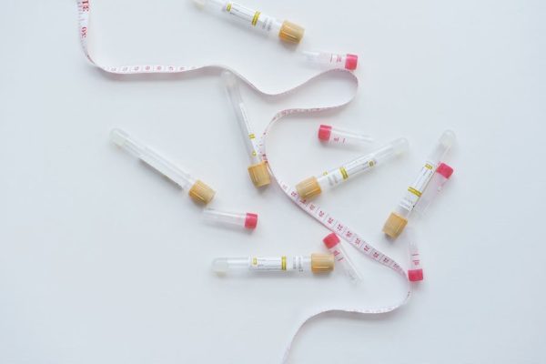 Flat lay of blood test tubes and a tape measure on a white background.