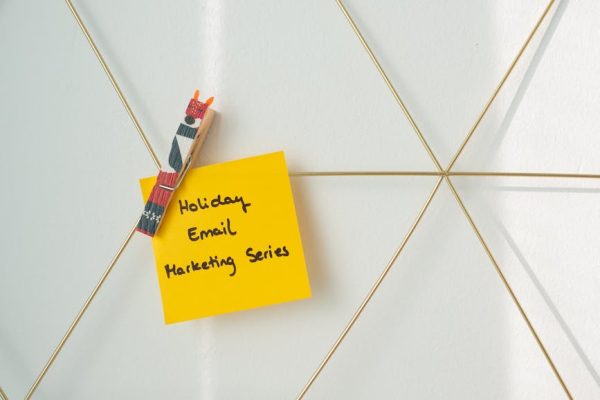 Bright yellow sticky note with holiday email marketing message clipped to a wireframe wall.