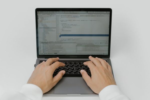 Close-up of hands coding on a laptop, showcasing software development in action.