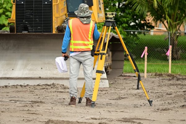 A surveyor with equipment conducts measurements on a construction site.