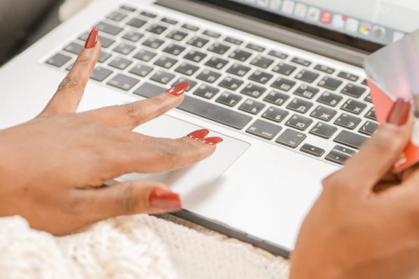 Close-up of hands on a laptop typing with a credit card for online shopping.