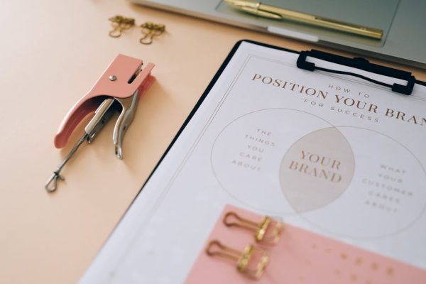Pink stapler and branding document on a desk showcasing stylish office setup.