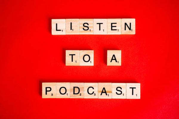 Scrabble tiles on red background forming the phrase 'Listen to a Podcast'.