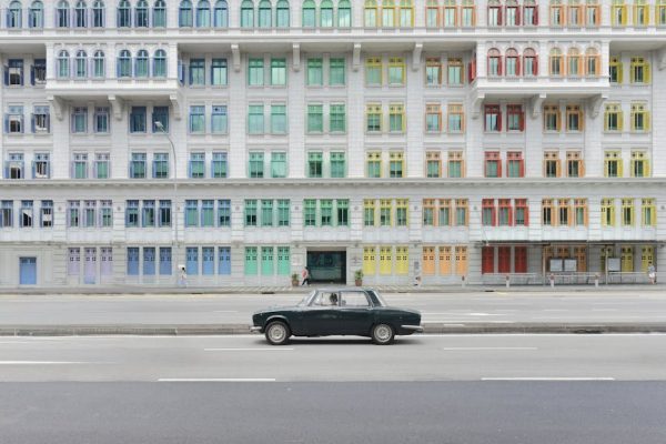 Vintage car parked in front of the vibrant Old Hill Street Police Station with colorful windows in Singapore.