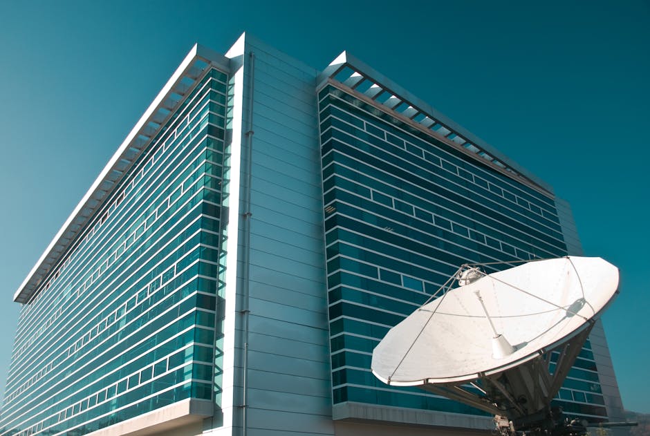 A striking modern glass building in Santiago, Chile, featuring a large satellite dish under a clear blue sky.