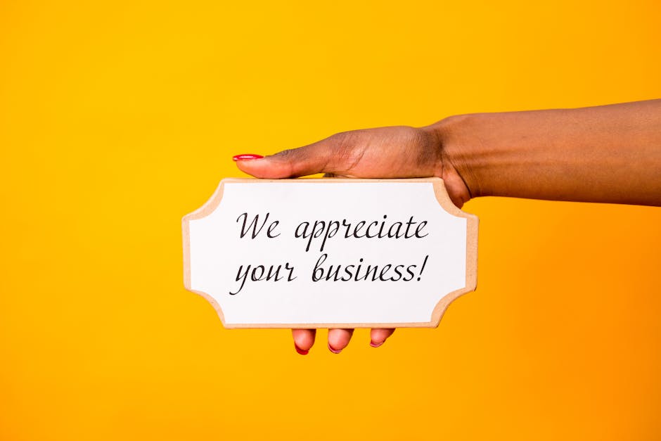 A hand holding a thank you sign with 'We appreciate your business!' on a vibrant yellow background.